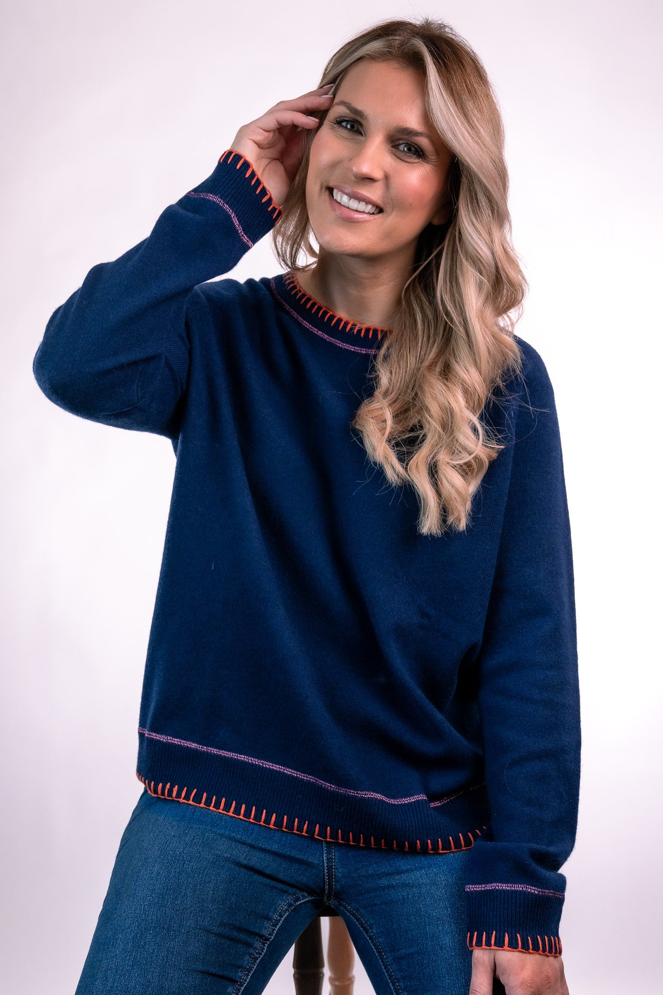 Navy cashmere raglan sweatshirt with orange blanket stitch detail to cuffs and hem, with pink lurex stitch detail