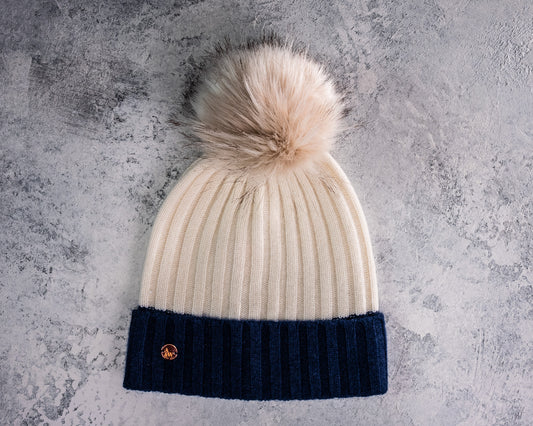 A colour block 100% Cashmere rib beanie in winter white and navy finished with a detachable faux fur pom 