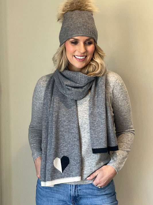 Grey cashmere plain knit beanie with faux fur pom and matching grey scarf with black & winter white intarsia heart design and end trim