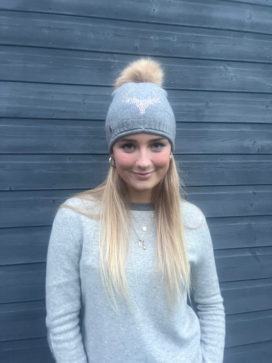 Grey cashmere plain knit beanie with a rose gold stag embellishment & faux fur pom